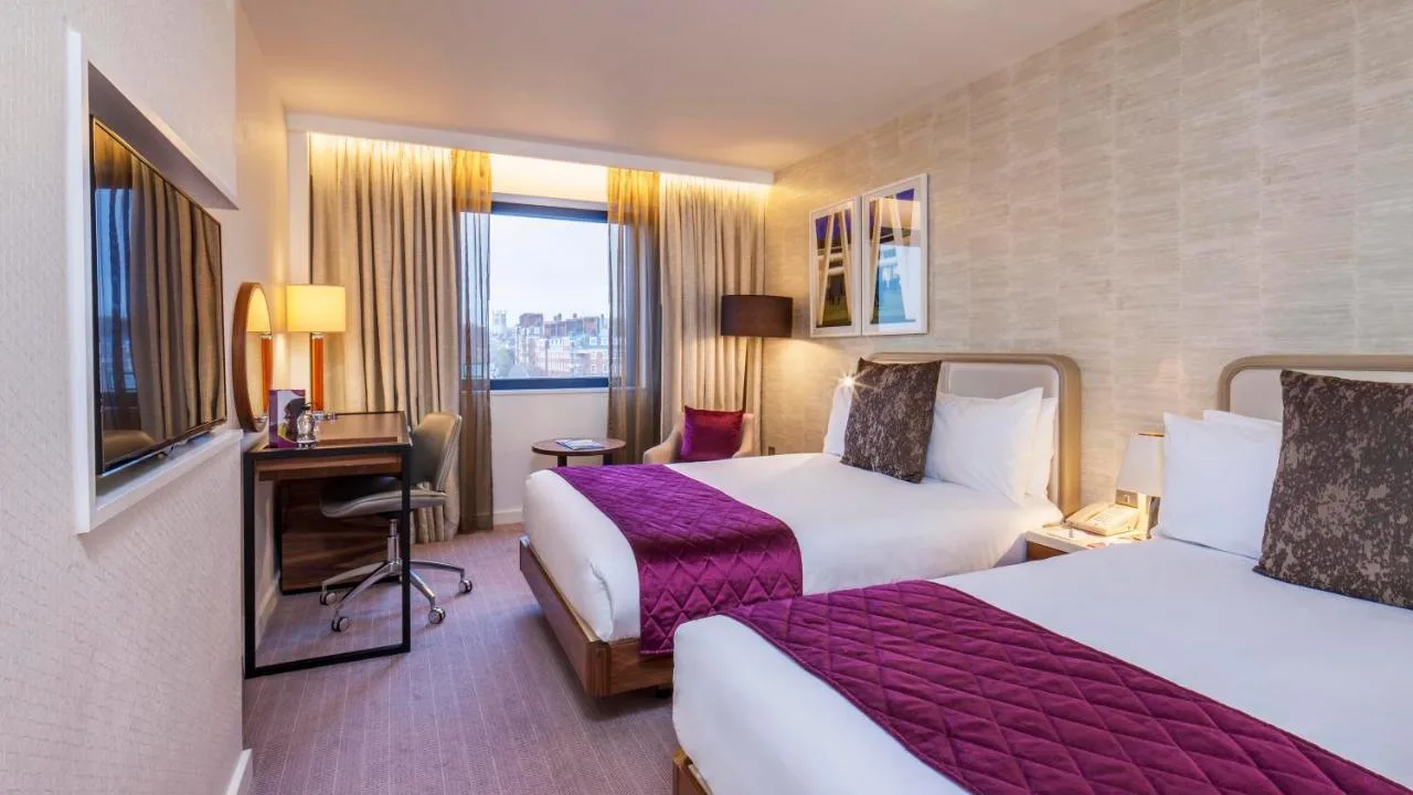 a hotel room with two beds and a desk at Crowne Plaza London Kings Cross by IHG in London