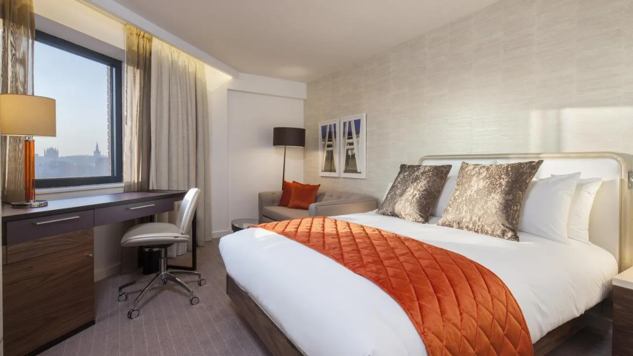 a hotel room with a bed and a desk and a window at Crowne Plaza London Kings Cross by IHG in London
