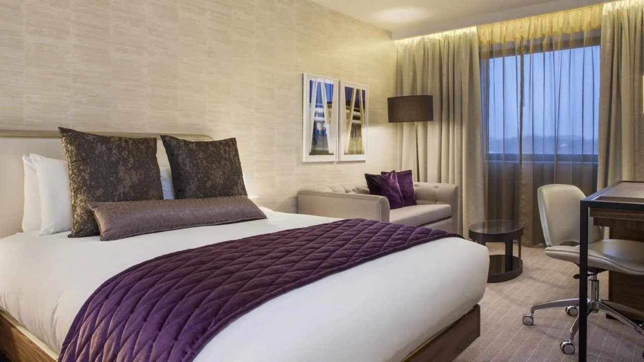 a hotel room with a large bed and a chair at Crowne Plaza London Kings Cross by IHG in London